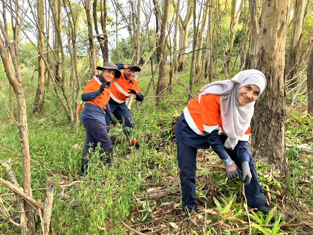 Greening Australia March 2025 Woman bending over and weeding in bushland.